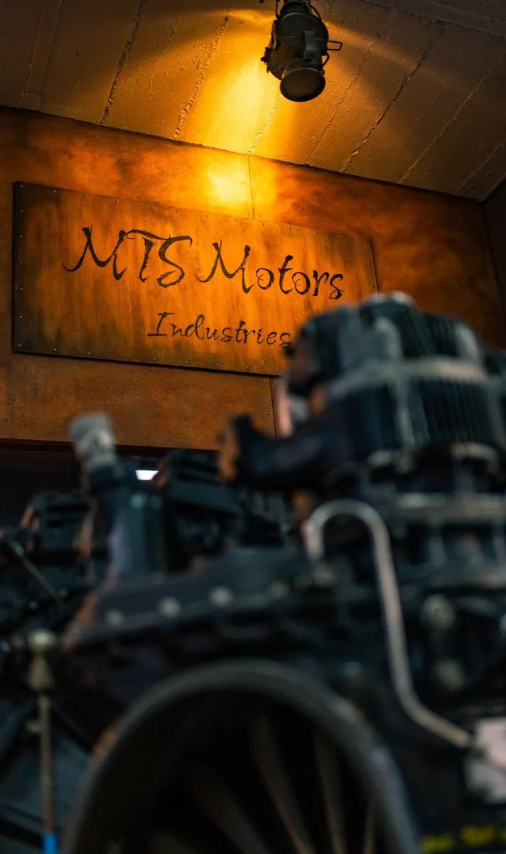 Schild «MTS Motors» im warmen Licht der Werkstatt