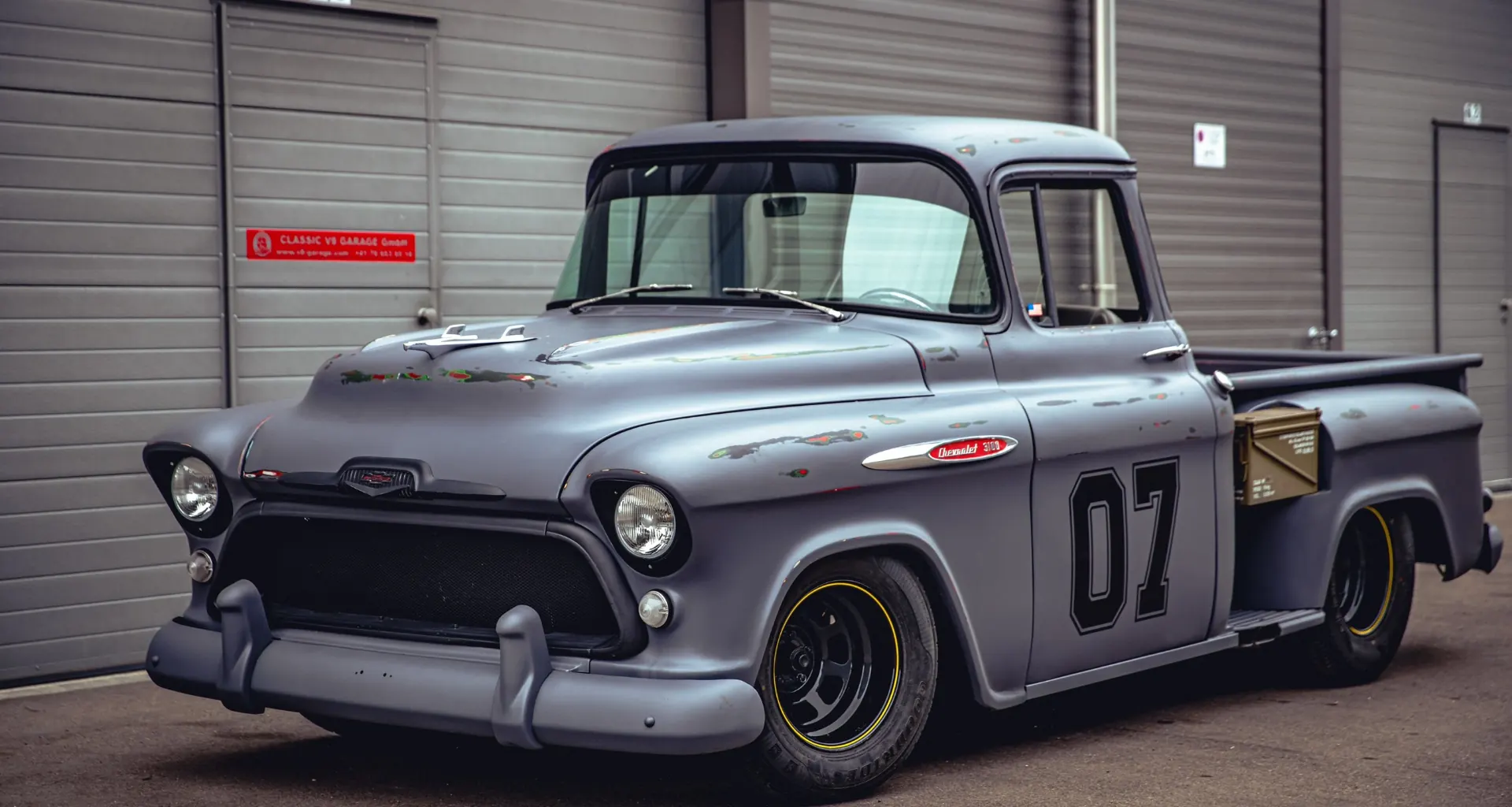 Grauer klassischer Pick-up mit Startnummer 07 vor der Halle